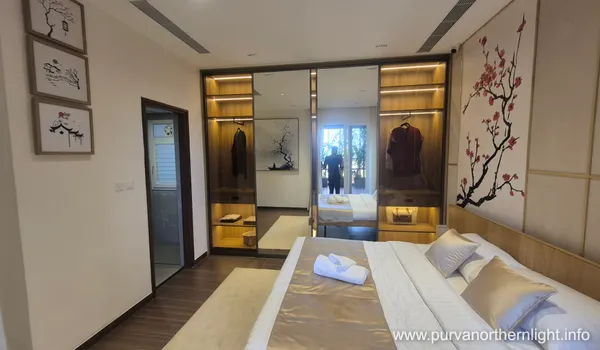Second bedroom in Purva Northern Lights 2 BHK featuring mirrored sliding wardrobes and minimalist floral wall art.