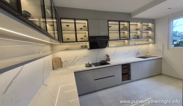 Luxury L-shaped modular kitchen at Purva Northern Lights featuring grey cabinets, marble-patterned backsplash, and integrated LED shelf lighting.