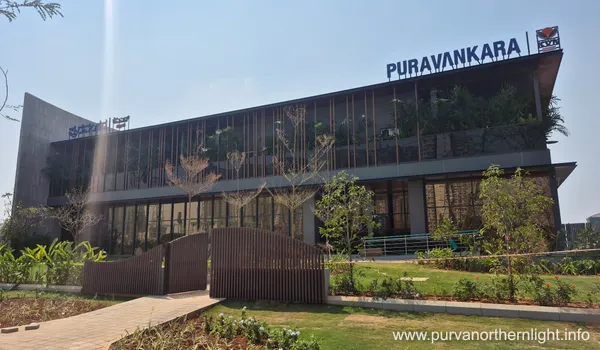 A modern two-story glass facade experience center for Purva Northern Lights with Puravankara branding and lush green landscaping in the foreground.